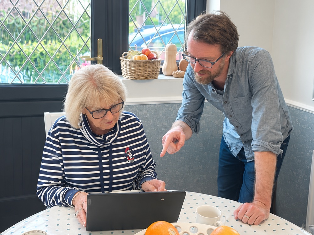 Ryan at a customer's kitchen table, pointing out something on her laptop